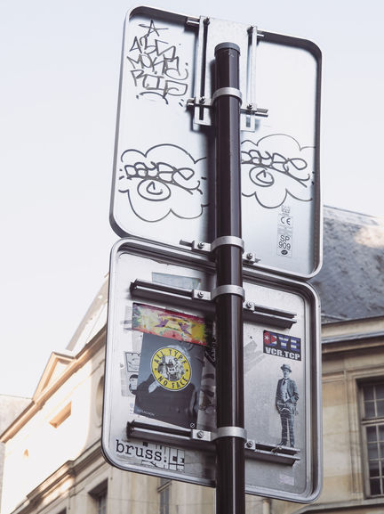 Street signs with graffiti and stickers attached.