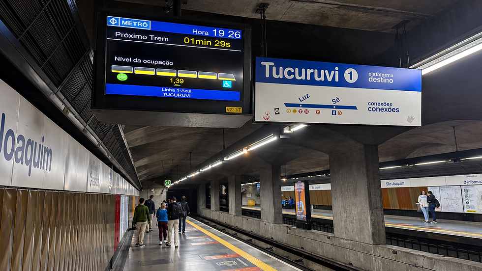 Plataforma de metrô Tucuruvi com passageiros, painéis mostrando próximo trem em 1 min 29 s e conexões; ambiente subterrâneo.