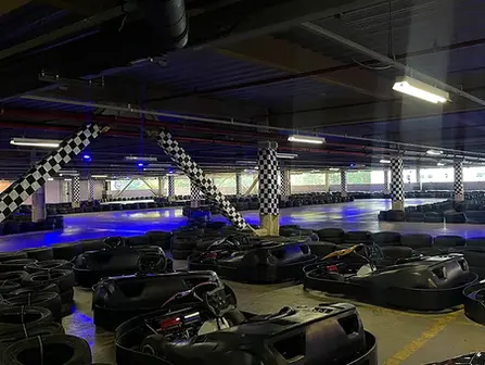 Pista de kart indoor com iluminação vibrante e karts prontos para a corrida.