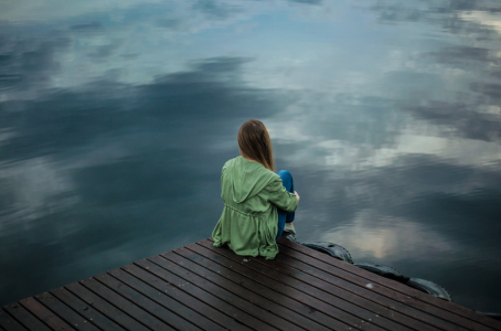 Frau sitzt erschöpft am dunklen See