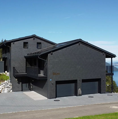Naturstein-Schieferfassade der Villa Tauris in Emmetten – langlebige, ressourcenschonende Architektur im Einklang mit der alpinen Landschaft und Beitrag zur lokalen Biodiversität durch natürliche Mikrohabitate.