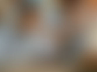 Smiling person in glasses works on a laptop in a cafe. Holographic charts showing data hover nearby. Warm and modern ambiance.