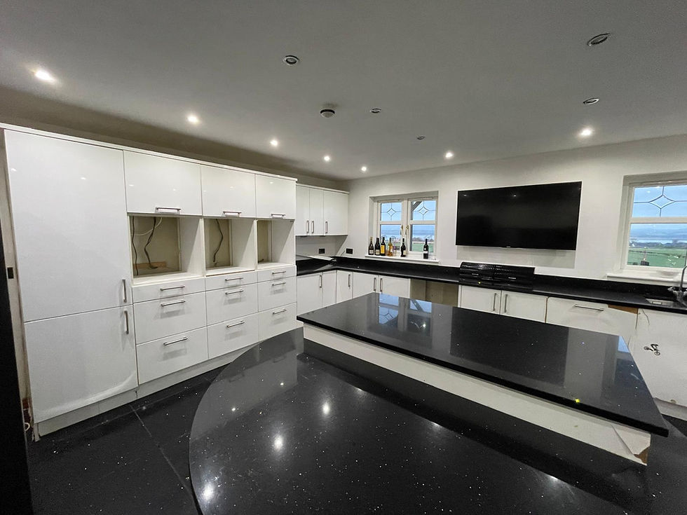 Wide landscape photo of a modern wrapped kitchen with glossy white cabinets and black sparkle worktops