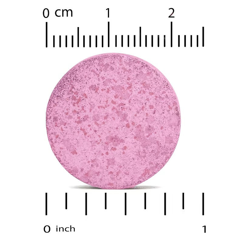 Miniatura: Comprimido masticable junto a una regla de referencia, para visualizar su tamaño real y textura.