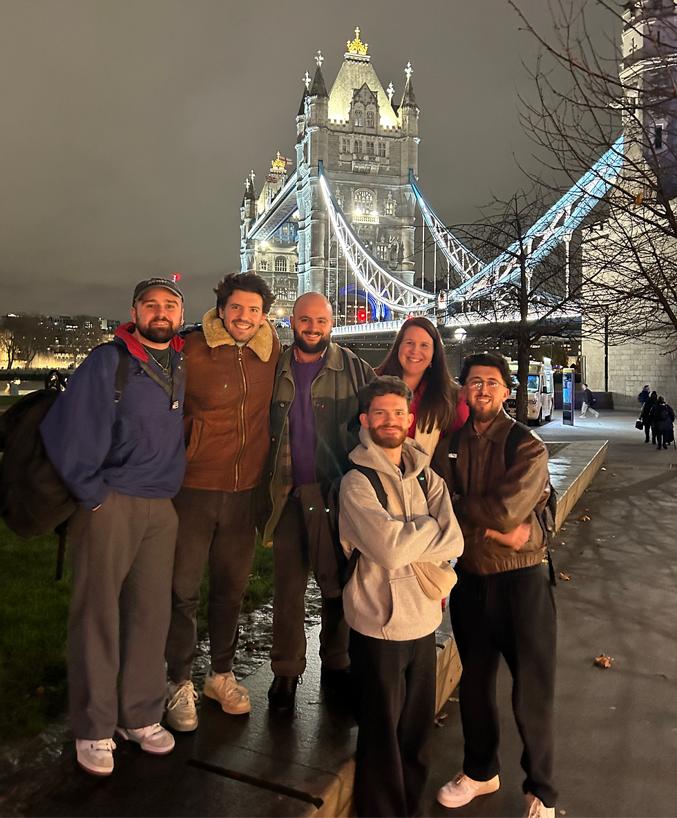 Jack Tricker, Julian Spooner, Fredi Monk Porcel, Samantha Streibl, Andy Hill & David Woolcott posing for a photo in front of Tower Bridge, London at night time.