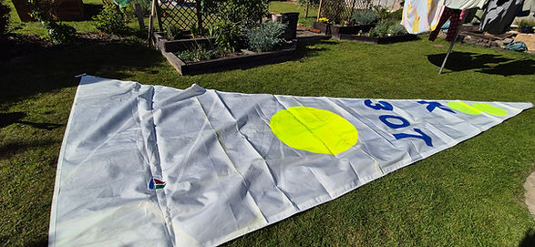 large white sail with yellow circle and numbers on a green