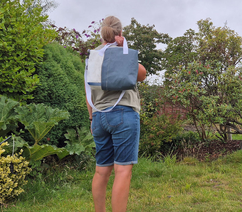 Thumbnail: Person carrying Blue and white Sail Bag with white handles and crossbody Strap over Shoulder. Garden Setting.