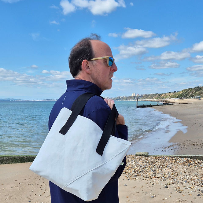 Man carrying a handmade upcycled sailcloth bag at the beach.