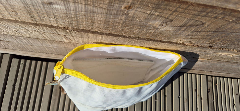 Thumbnail: White Toiletry Bag with yellow zip open view inside the bag, sitting on wooden decking in front of a fence