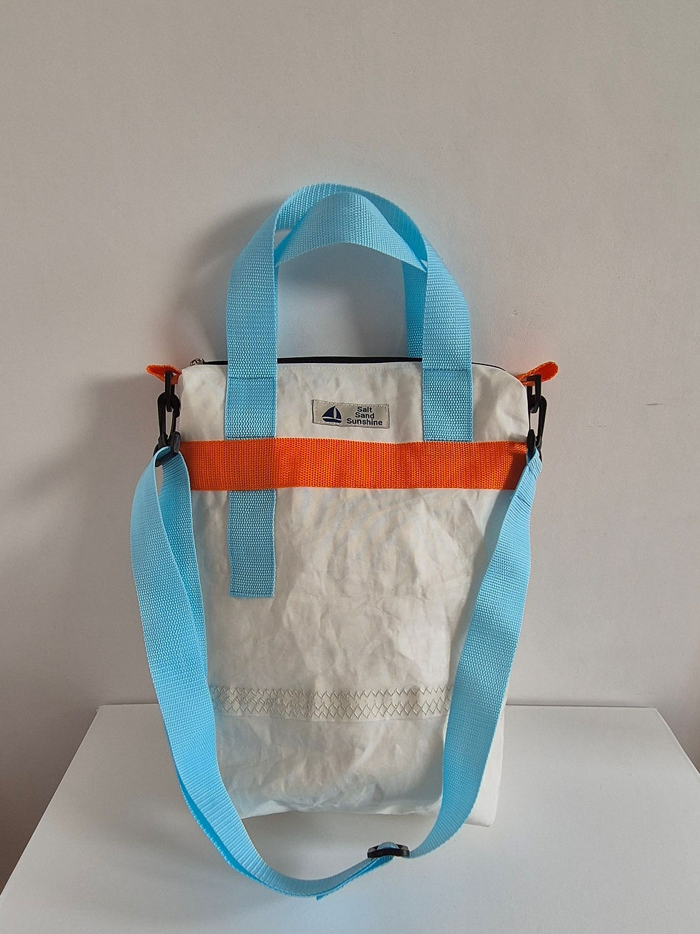Thumbnail: White Sail Bag with orange strap at the top, original stitching on lower half, light blue handles on either side hanging