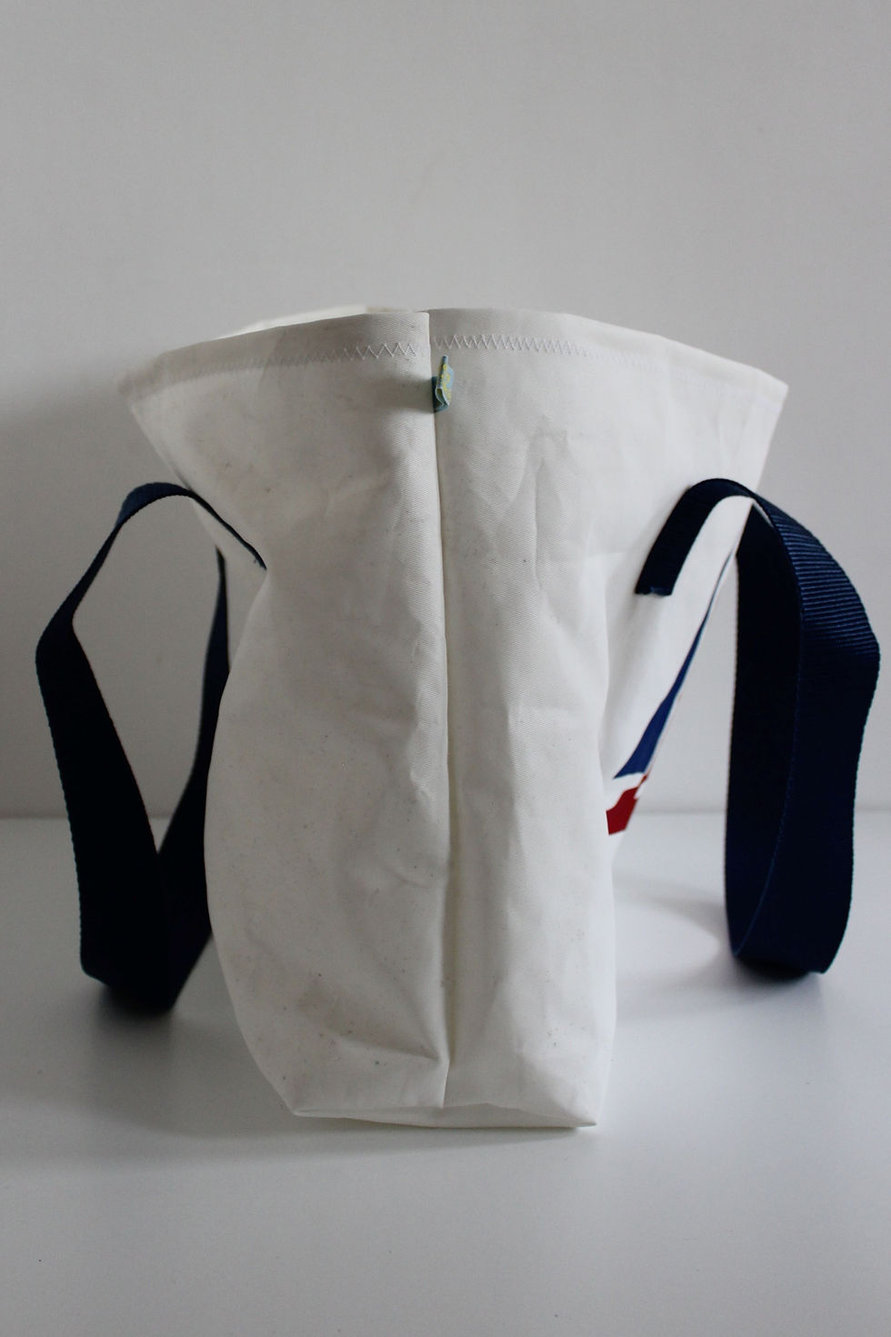 Thumbnail: side view of the white sail bag with blue handles. two seams come together