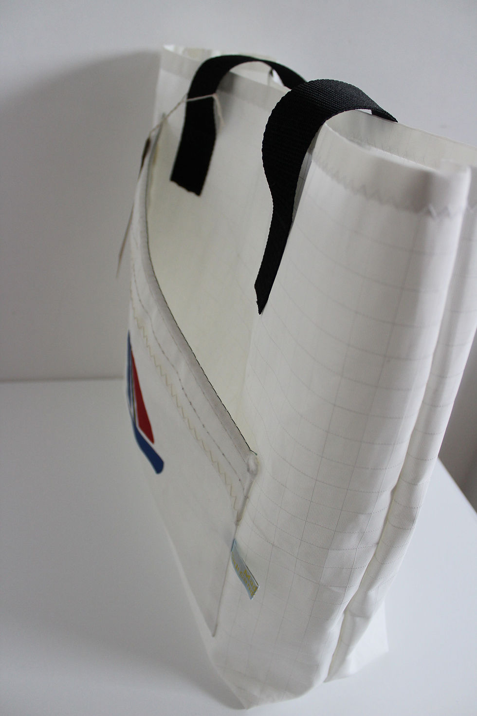 Thumbnail: side view of white sail bag with pocket at the front with black handles