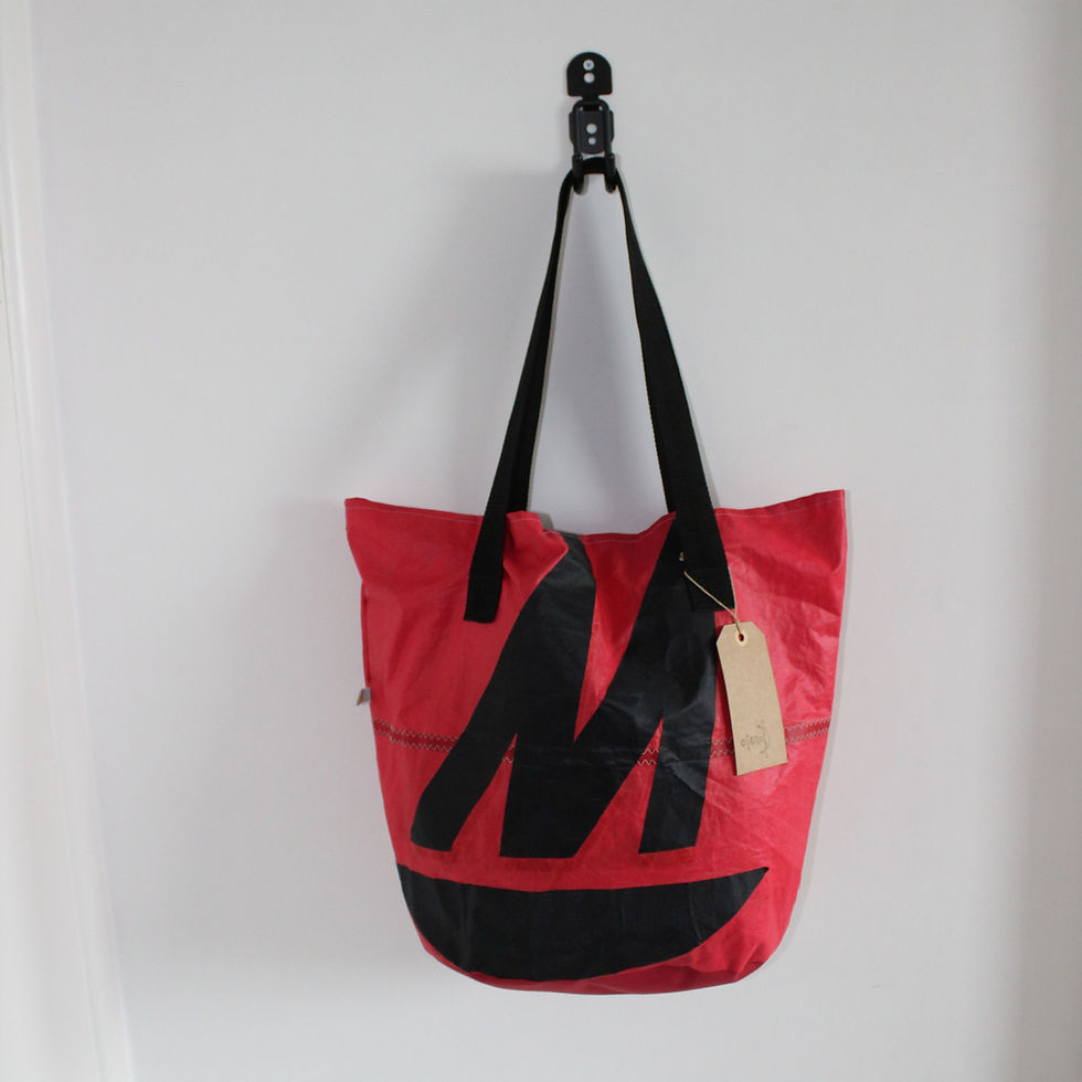 Thumbnail: front view of red sail bag with original M, hanging with black handles from a hook white background