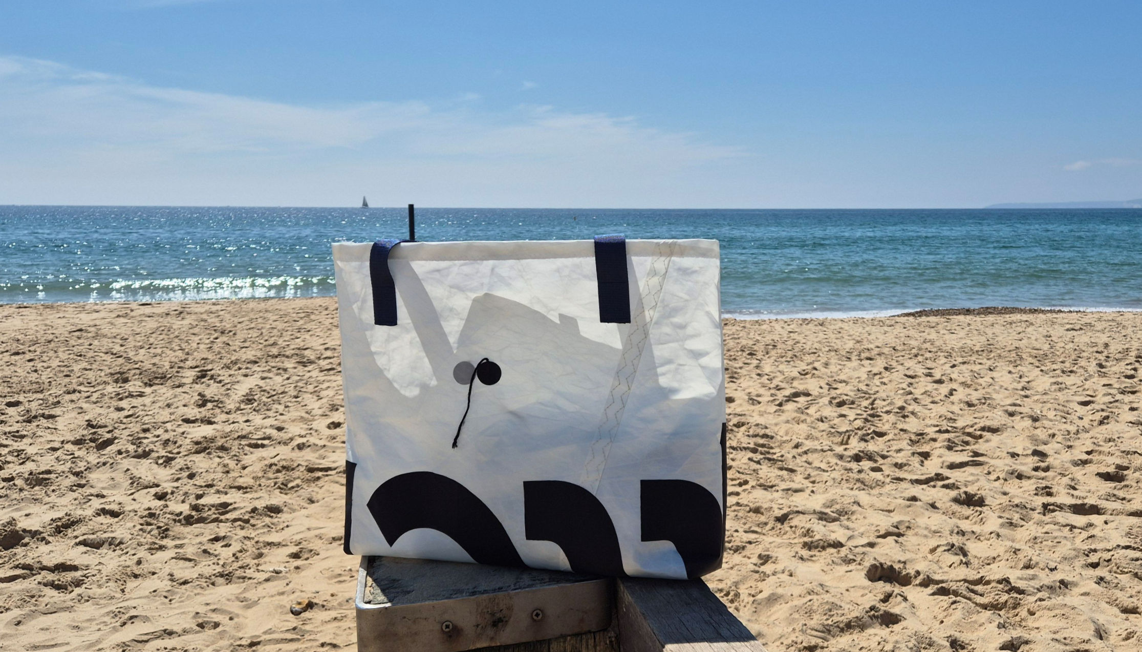 White Sail Bag with original stickers and blue Handles on Beach side