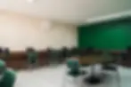 Sala multimídia moderna e espaçosa, com mobiliário em tons de verde e tablets interativos, ideal para aulas dinâmicas e apresentações multimídia.