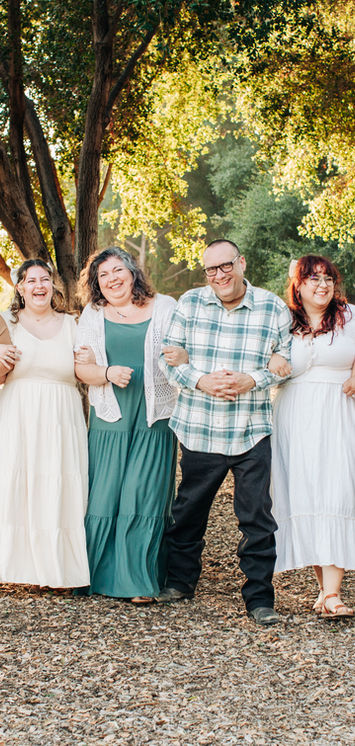 Family laughing as they walk arm and arm among the trees