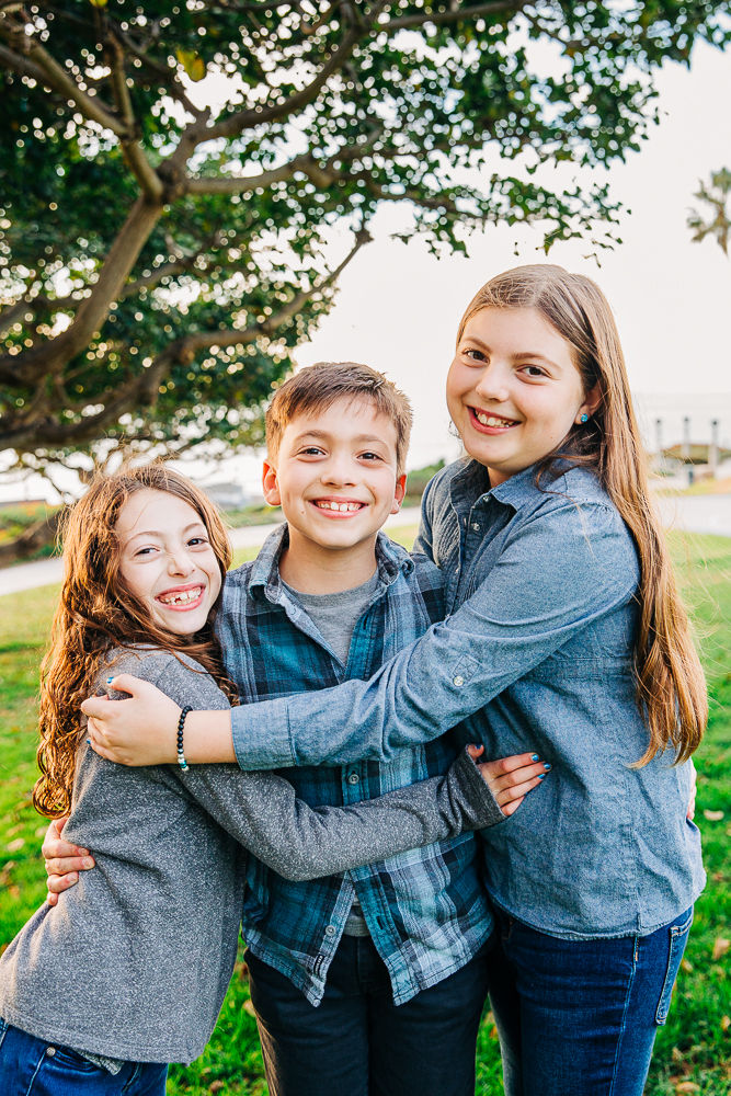 two sisters squeeze their brother