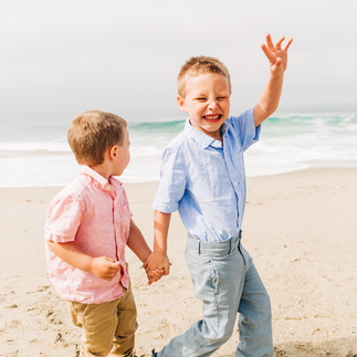 older brother leading younger brother to ocean