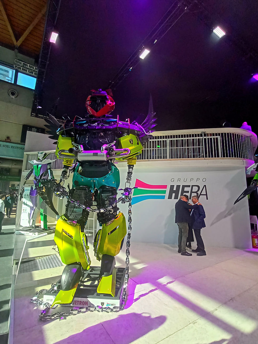  This stand captures attention with a highly creative and immersive stand featuring a massive, colorful robot figure under dramatic lighting, creating a memorable experience for the large crowd of attendees. @MBA Photography