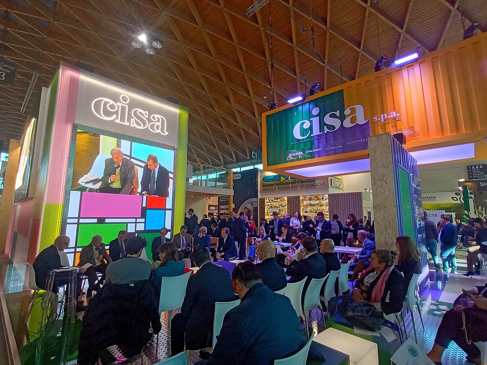 A vibrant and colorful stand serves as a central hub, hosting a focused panel discussion or presentation with a large, engaged audience, effectively blending business with eye-catching design. Photo Credits @MBA Photography