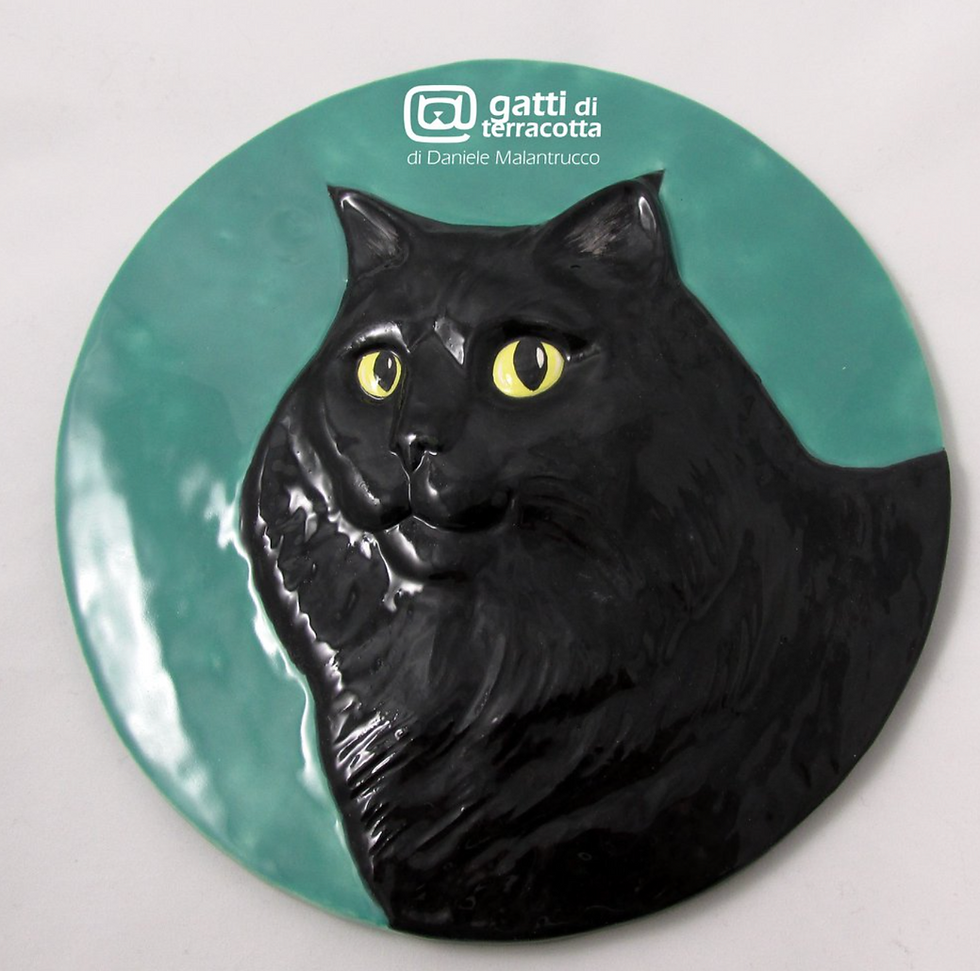 Un gatto nero ritratto su una piastrella di ceramica