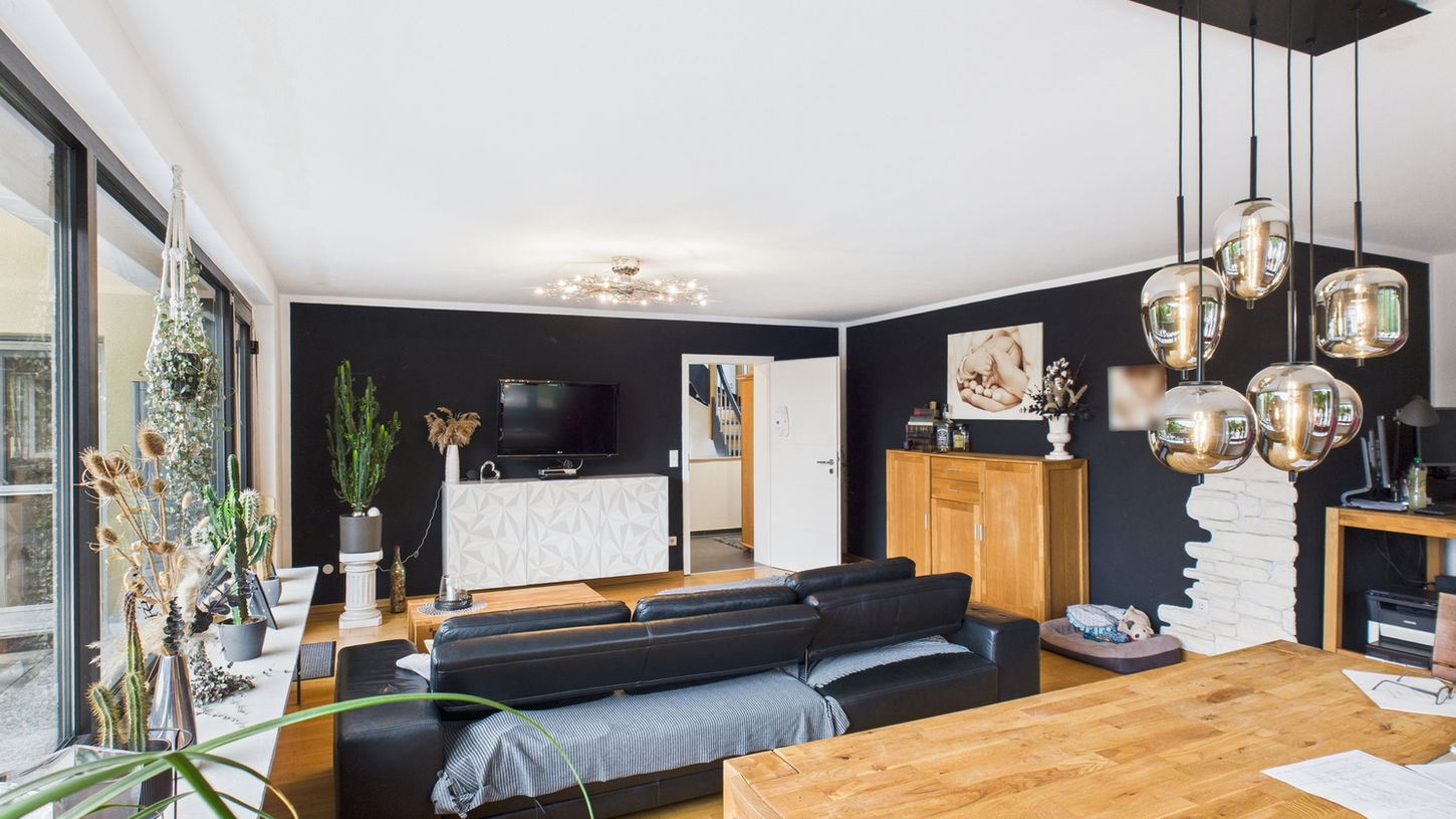 Modernes Wohnzimmer mit Esstisch und schwarzer Wand