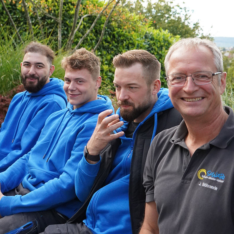 Das Team von Rollläden-Experten lächelt im Freien.