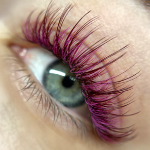 macro of colorful volume lashes in shades of magenta, black cherry, and wine on a blue eyed woman on Virginia Beach, Virginia