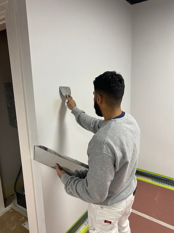 A painter repairing a hole in an interior wall.