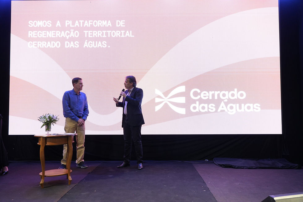 Visão ampla do palco do Fórum Regeneração Territorial 2026, com Marcelo Urtado, presidente do Cerrado das Águas, e Rodolfo Osório de Oliveira, chefe-geral da Embrapa Café, durante a apresentação da cooperação institucional. Ao fundo, um grande telão exibe a mensagem “Somos a plataforma de regeneração territorial Cerrado das Águas” e o logotipo da organização.