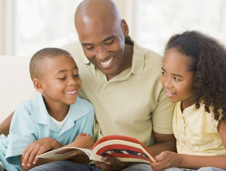 Black father reading to his children. Family. Happy. Quality Time.