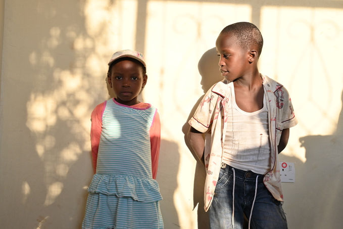 Two children are leaning against the wall in the sun