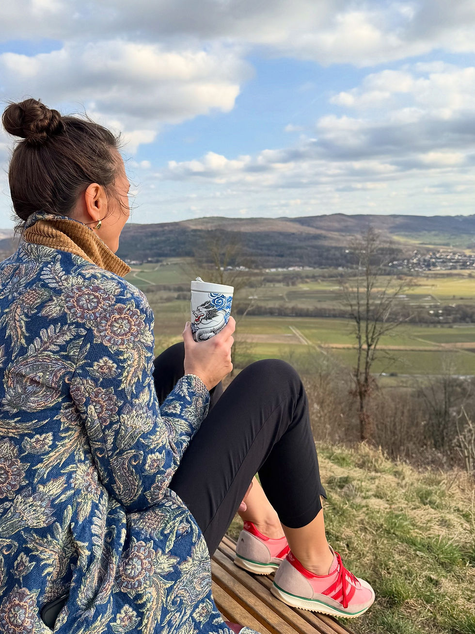 Frau sitzt ruhig auf einer Bank in der Natur und blickt in die Weite, Symbol für Reflexion, Selbstführung und emotionale Reife im Coaching/ Mentoring persönlicher Entwicklung