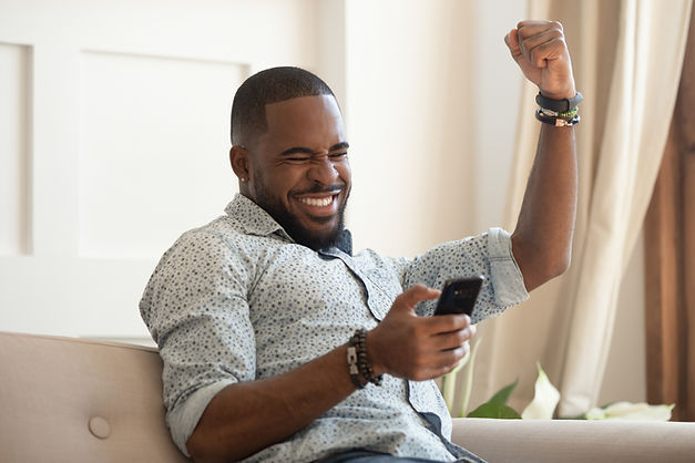 Excited overjoyed black man winner holding smartphone feeling euphoric with mobile online