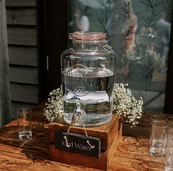 Glass water dispenser decorated with baby's breath flowers at an event
