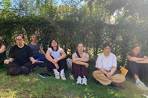 Une photo d'étudiantes et professeurs d'architecture de professeurs, assises dans un jardin, en pleine méditation guidée.