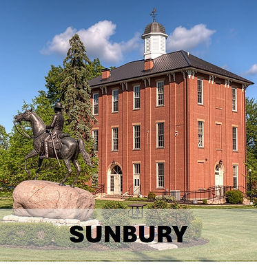 A bronze statue of a soldier on horseback in front of the historic Sunbury Ohio town hall building.