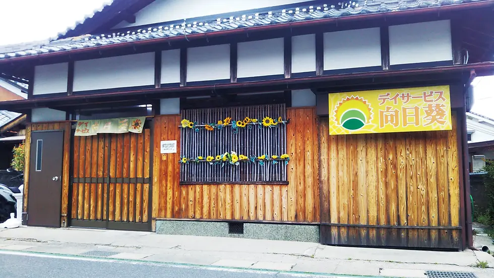 京都風の木造外観に『デイサービス向日葵』の看板が掲げられた介護施設の建物.webp