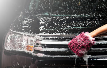 Hand washing a dark car with soap suds