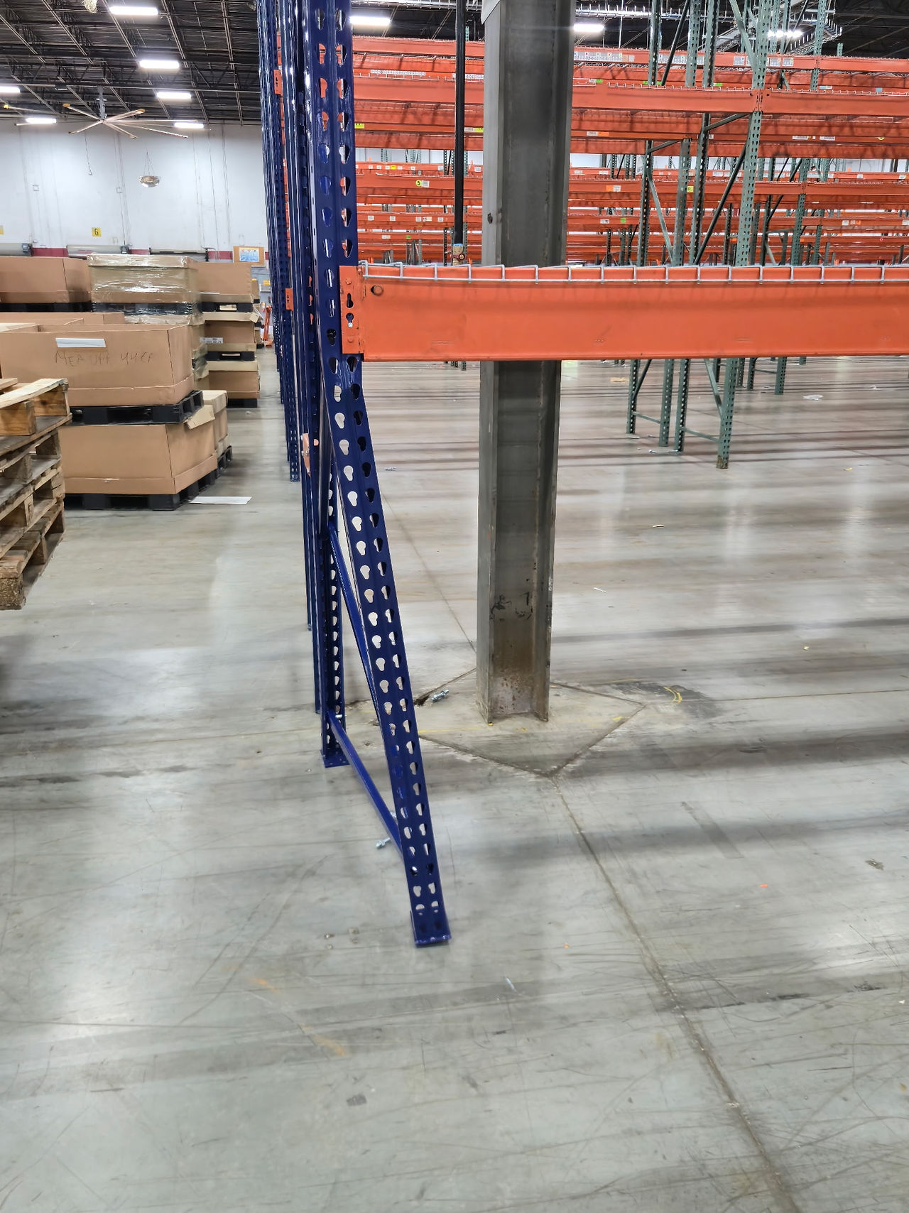 Bent pallet rack upright post showing visible deformation from forklift damage in a warehouse.