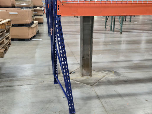 Bent pallet rack upright post showing visible deformation from forklift damage in a warehouse.
