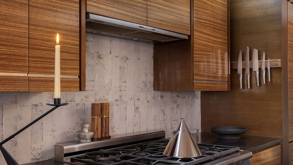 Zebrawood kitchen cabinetry with black countertops, stainless gas range and white tile backsplash