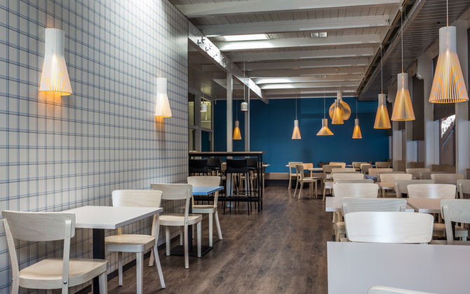 Restaurant im Holzbau des Tenniscenters. Das Konzept enthält viel Holz, warme Beleuchtung und frische blaue Akzente