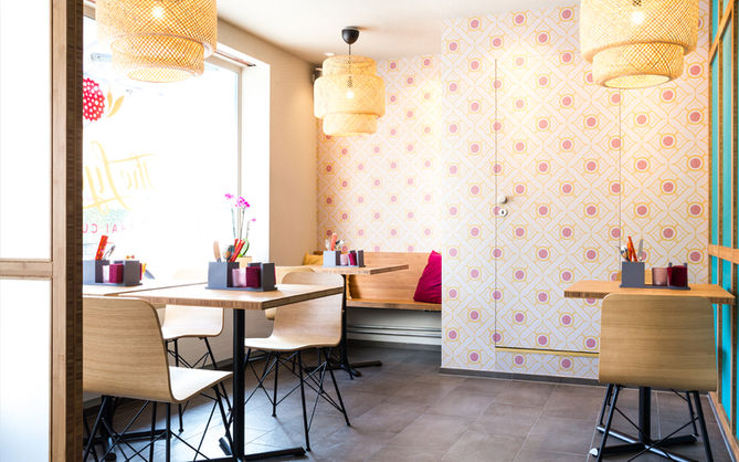 Raumecke des Restaurants mit Bambus Mobiliar, Bambus Leuchten und ornamentaler Tapete, die das Logo des Restaurants aufgreift