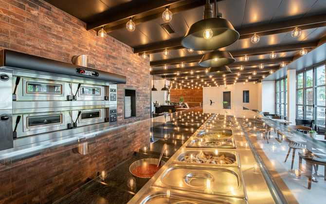 Blick auf eine Pizzaiolo Station im Restaurant, Leuchten spiegeln sich in der Glasabdeckung