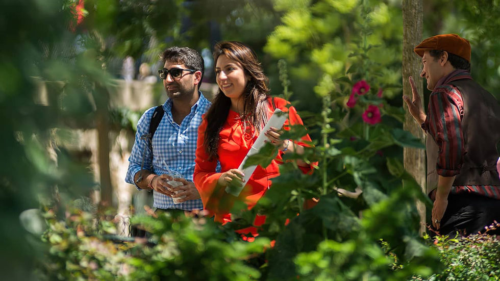 Mujer con vestido rojo y hombre con camisa azul caminando en una plaza de Montmartre en París