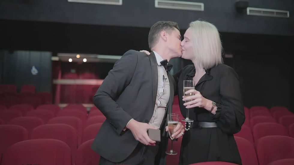 Man in a suit and elegant blonde woman kissing in a Parisian cinema during a surprise Paris proposal