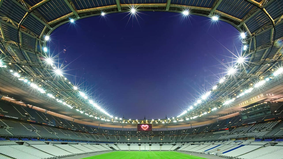 Το Stade de France φωτισμένο νυχτερινά, με ένα φωτεινό κόκκινο καρδιογράφημα εμφανισμένο στη μεγάλη οθόνη του σταδίου