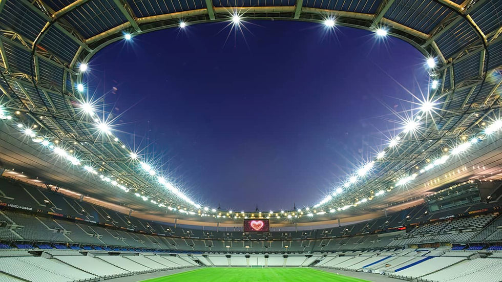 Estádio de France iluminado à noite, com um coração vermelho luminoso na tela gigante