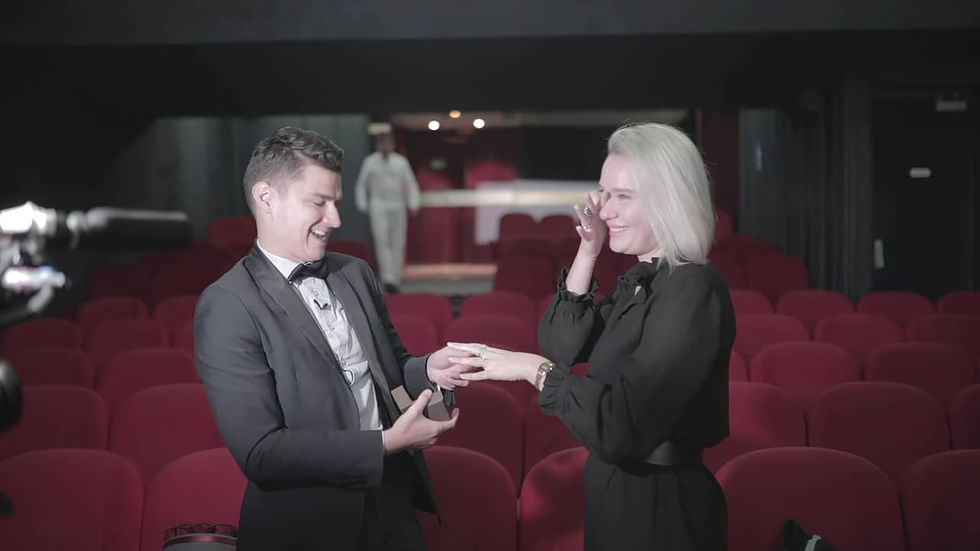 Young man in a suit holding the hand of his tearful partner during a wedding proposal in a cinema